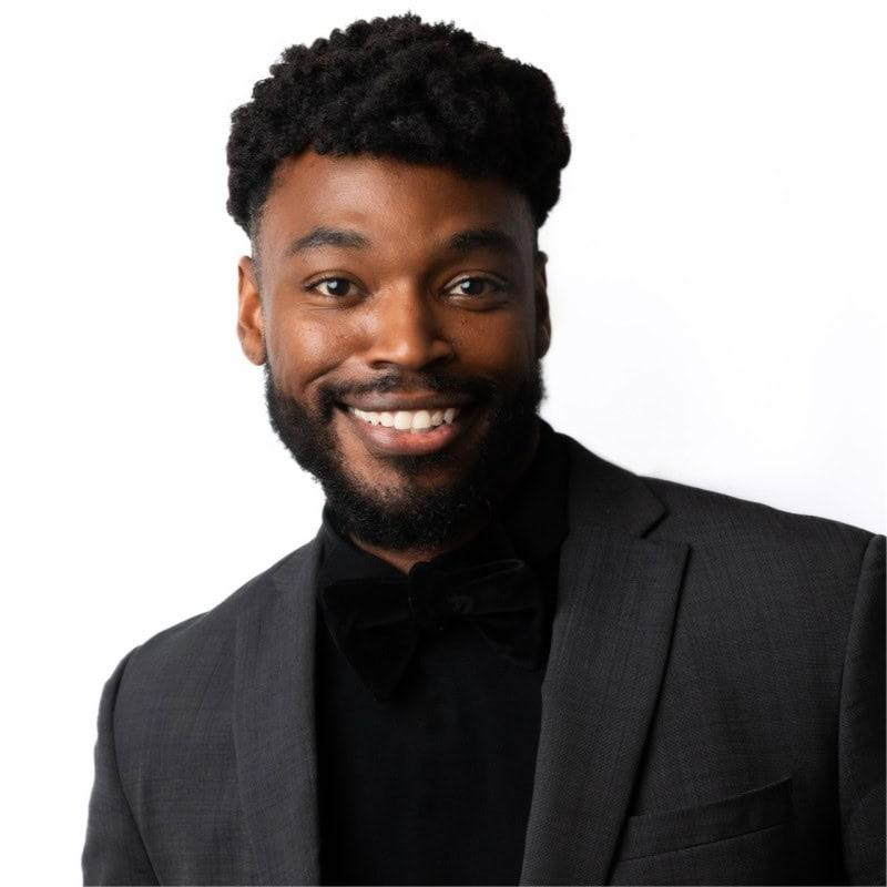 Justin Foster, smiling in a black suit and bow tie